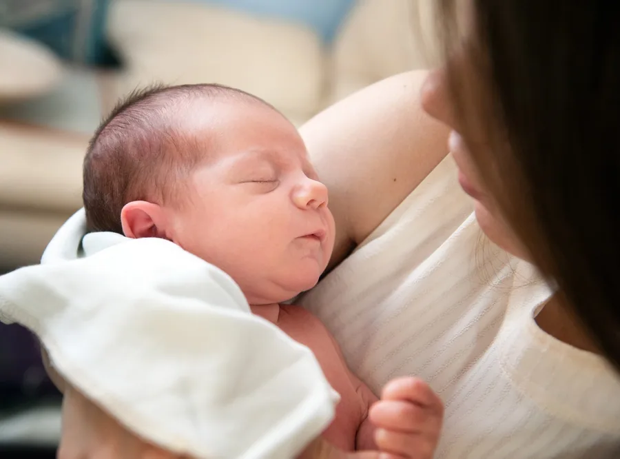 Neugeborenes auf dem Arm der Mutter